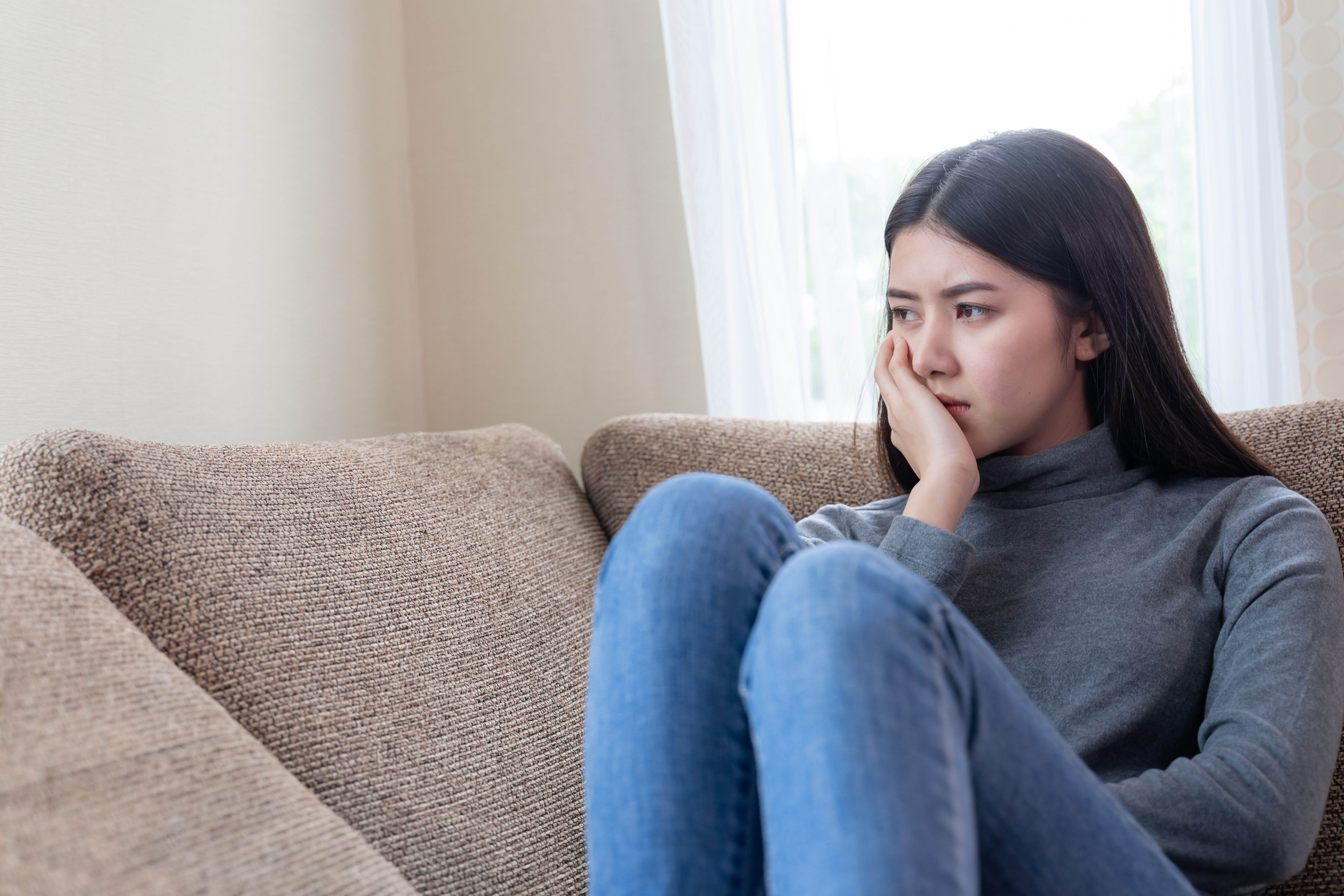 Ilustrasi wajah wanita muda introvert yang tidak bahagia duduk sendirian di sofa
