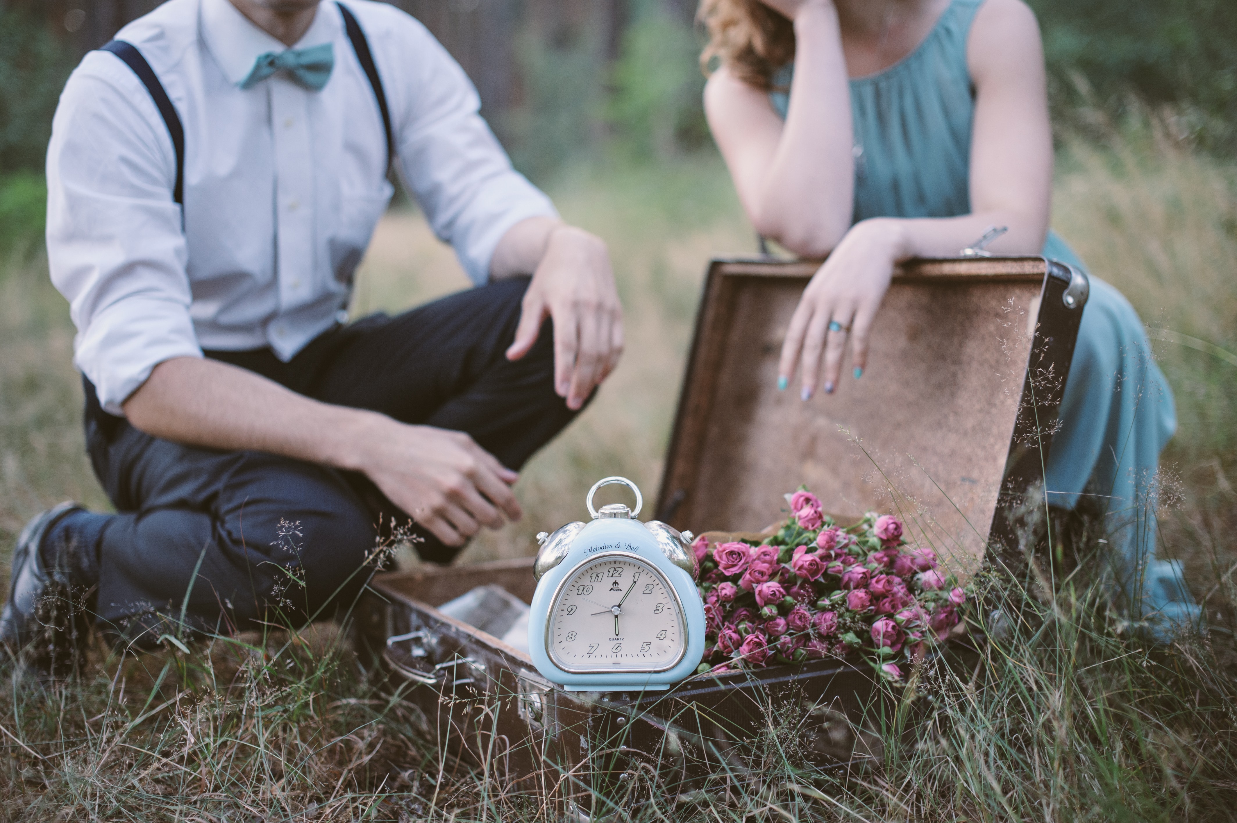 sepasang kekasih duduk di foto bangku kayu coklat sambil menatap waktu