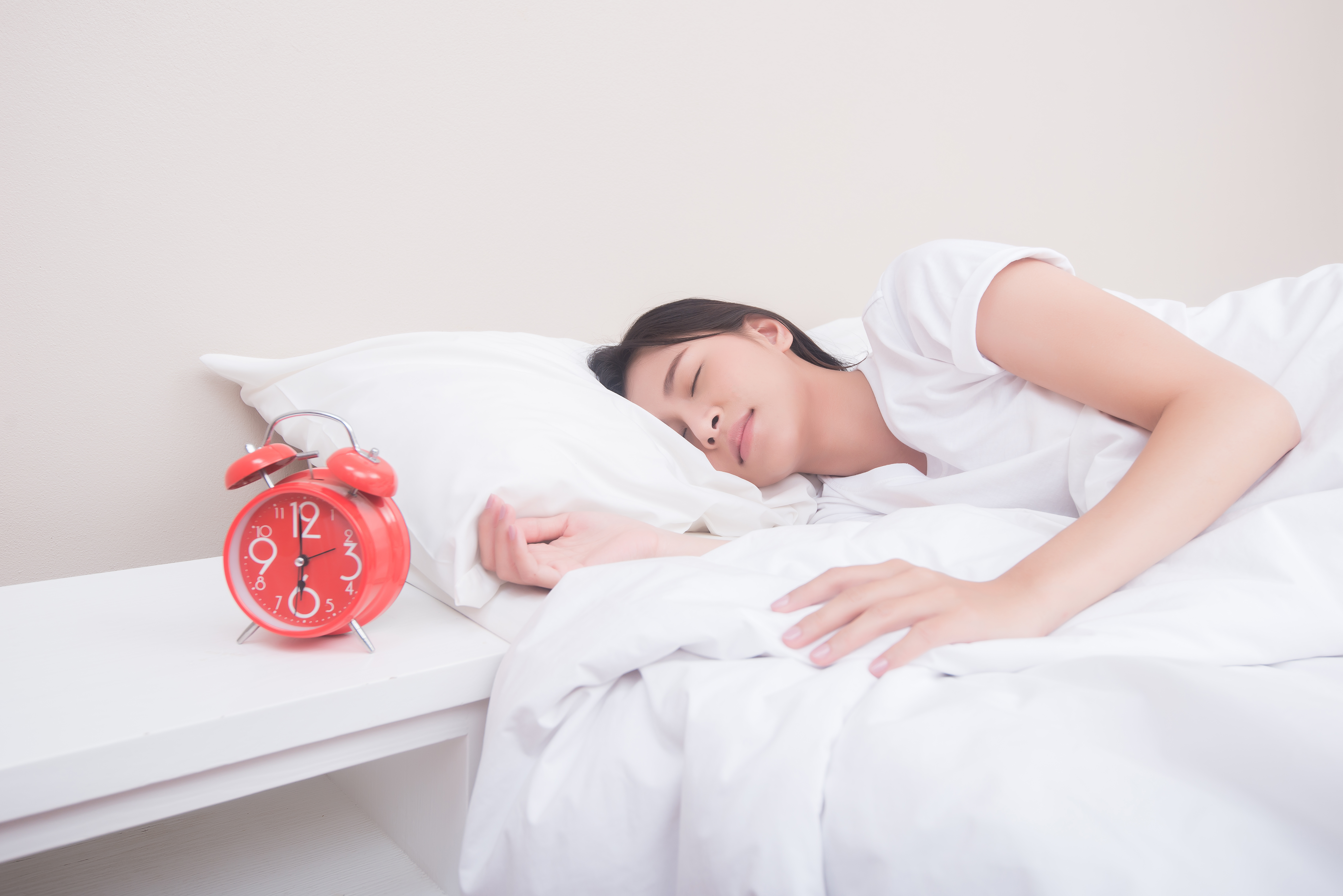 wanita tidur di tempat tidur samping jam alarm